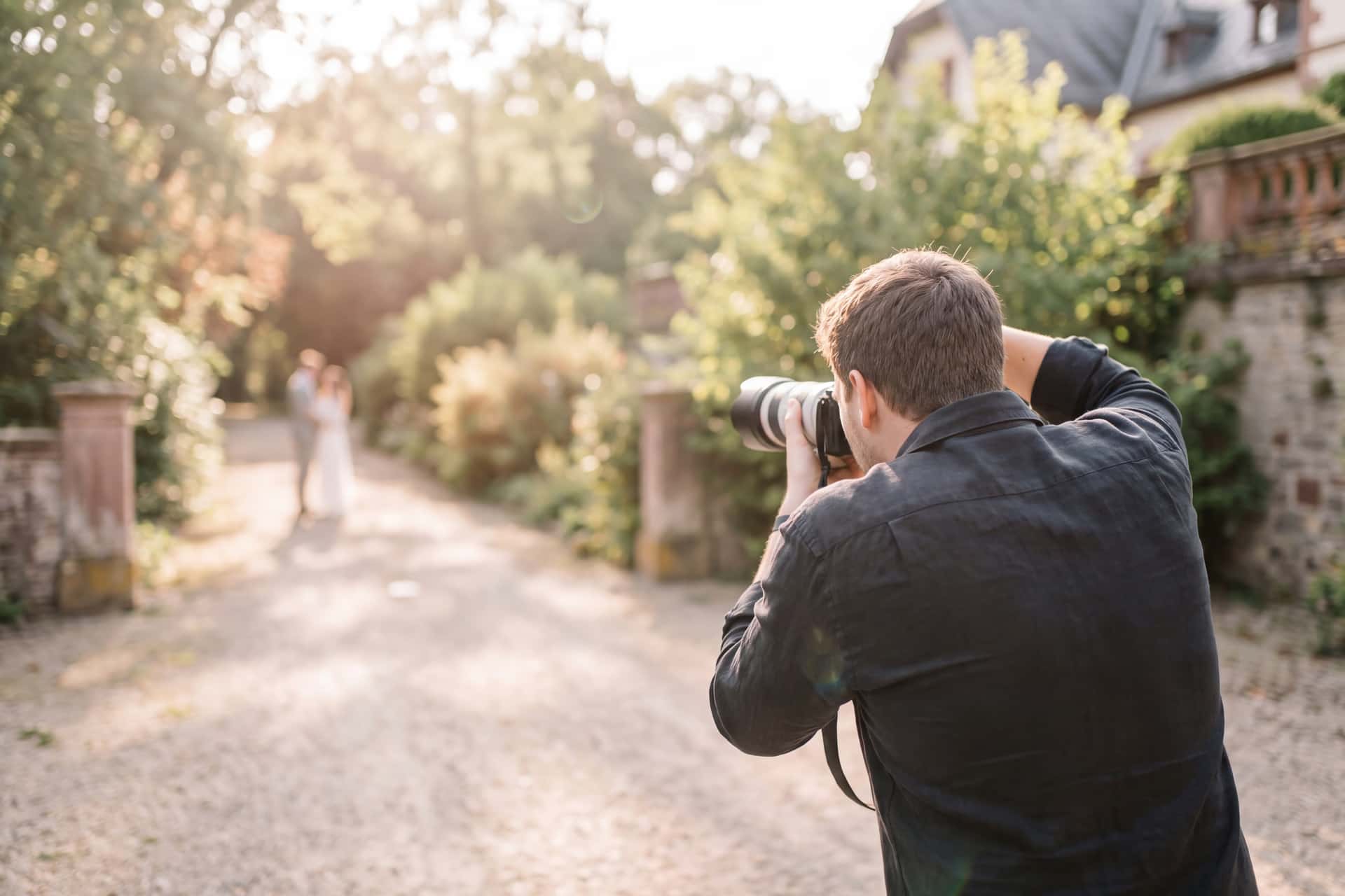 Hochzeitsfotograf mit Kamera bei einem Paarshooting im Grünen — Hochzeitsfotograf Pfalz Villa Renting Eisenberg