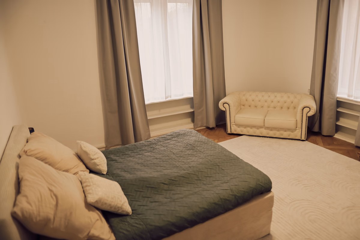 Schlafzimmer der Hochzeitssuite mit Bett, grünem Plaid und Chesterfield-Loveseat, Villa Renting Eisenberg Pfalz