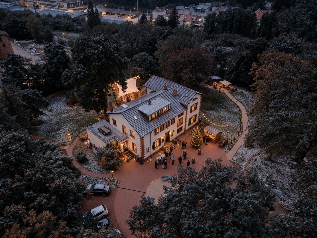Luftbild vom Vorplatz der Villa Renting mit Besuchern, Lichterketten und Tannen im Winter